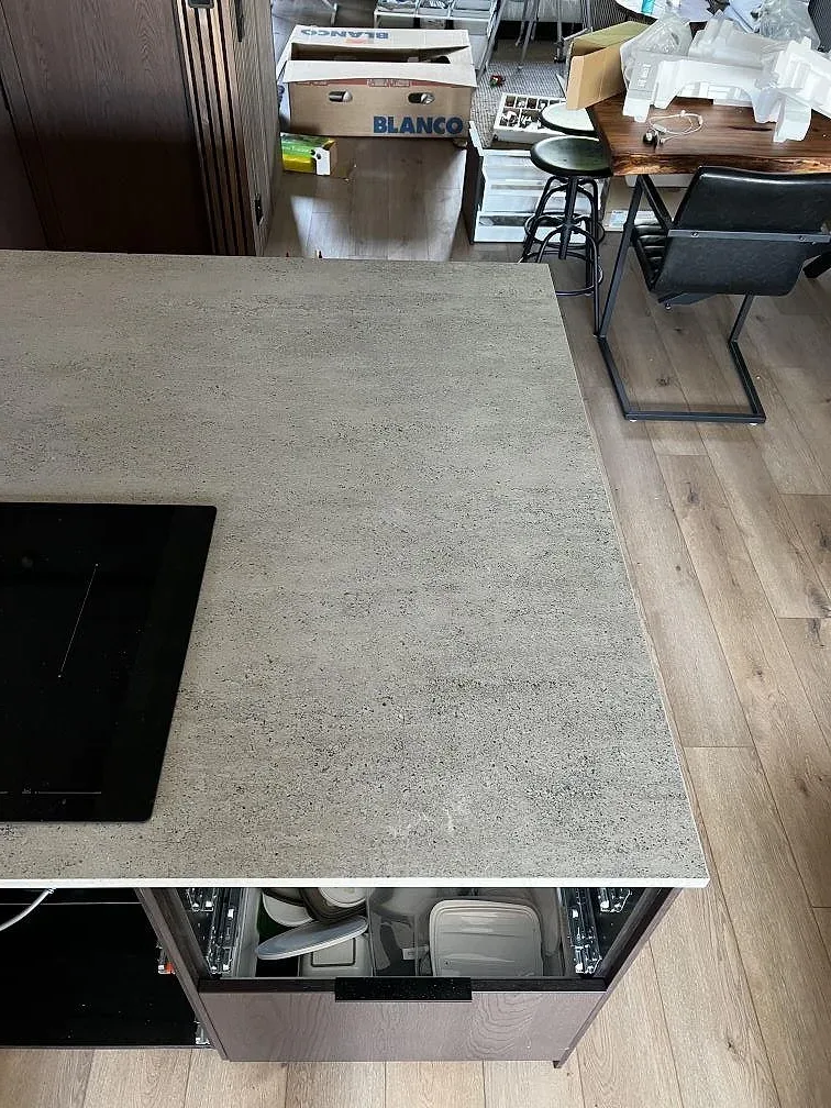 Köksö och arbetsyta i matt Dekton Keon med betonglik grå yta och svart häll i ett kök i Falkenberg.