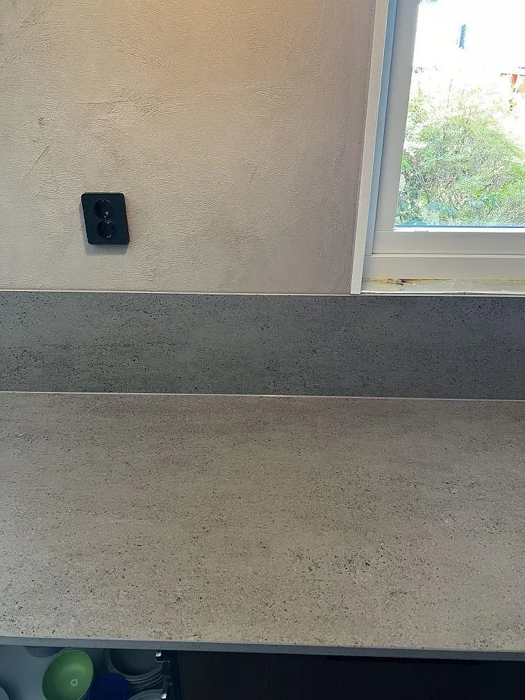 Närbild av matt Dekton Keon med betonglik yta, vertikal detalj och köksbänk vid stort fönster i Falkenberg.