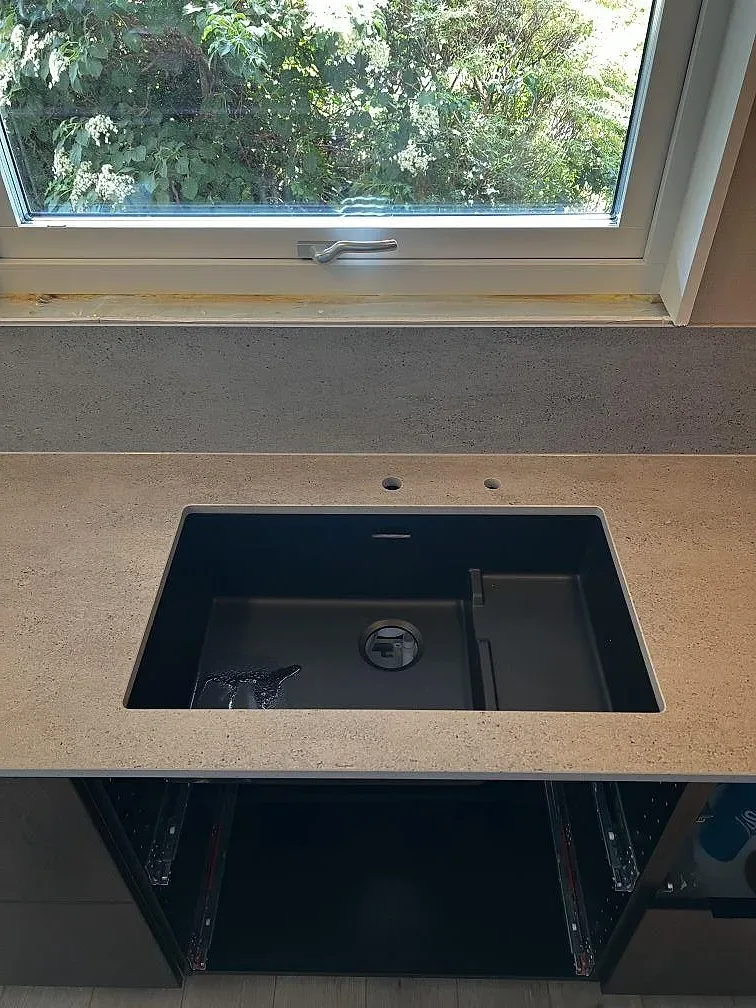 Detalj av svart underlimmad diskho i matt Dekton Keon med grå keramikyta vid fönster i Falkenberg.