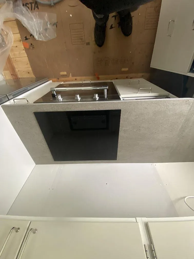 Köksbänkskiva i grå Dekton Keon med infälld svart induktionshäll i ett kök i Göteborg, matt betongliknande stenyta.