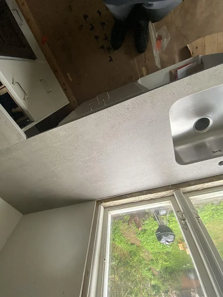 Köksbänkskiva i grå Dekton Keon vid fönster i ett kök i Göteborg med underlimmad rostfri diskho i den matta stenytan.
