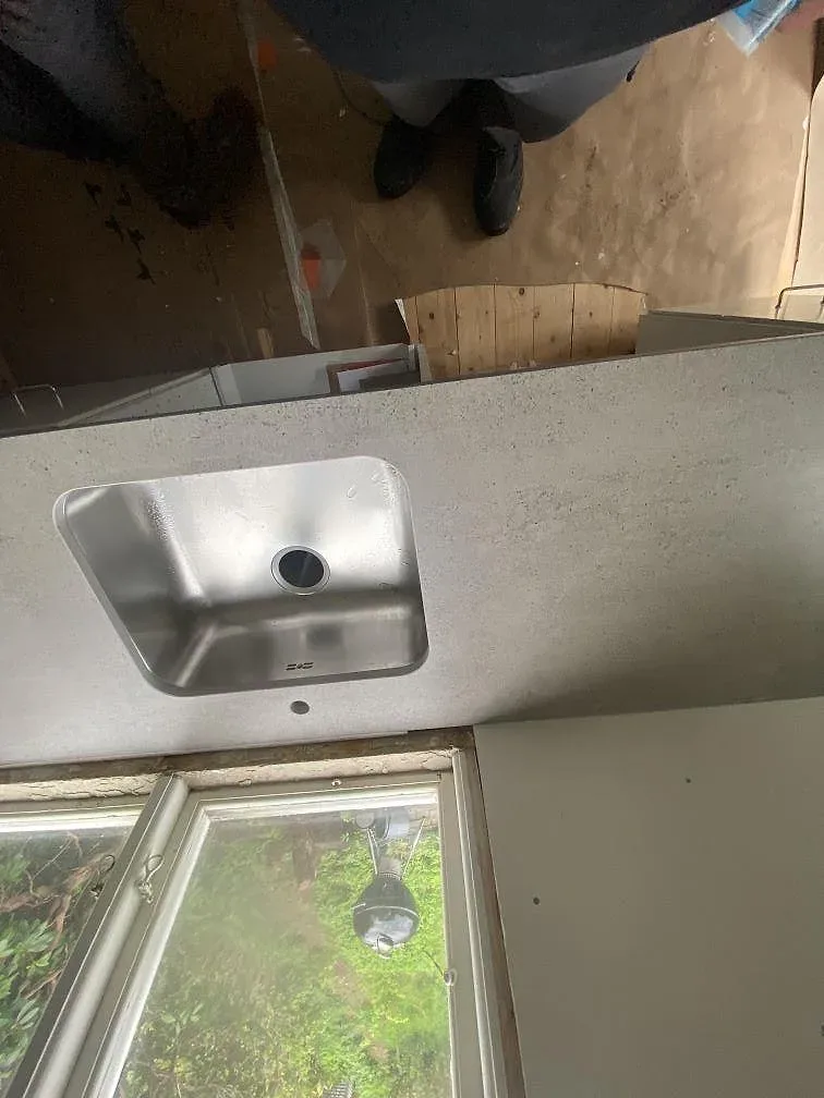 Detalj av underlimmad rostfri diskho i grå Dekton Keon köksbänkskiva, matt yta, i ett kök i Göteborg.