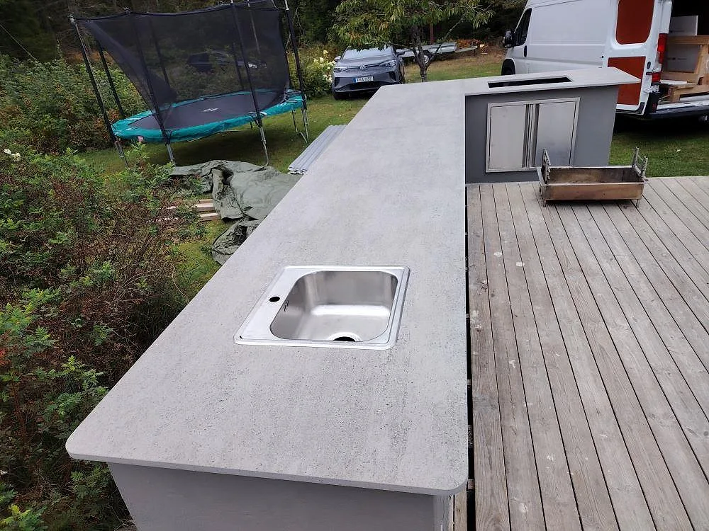 Närbild av matt Dekton Keon som bänkskiva i utekök i Grisslehamn, med rostfri diskho och den långa skivytan synlig.