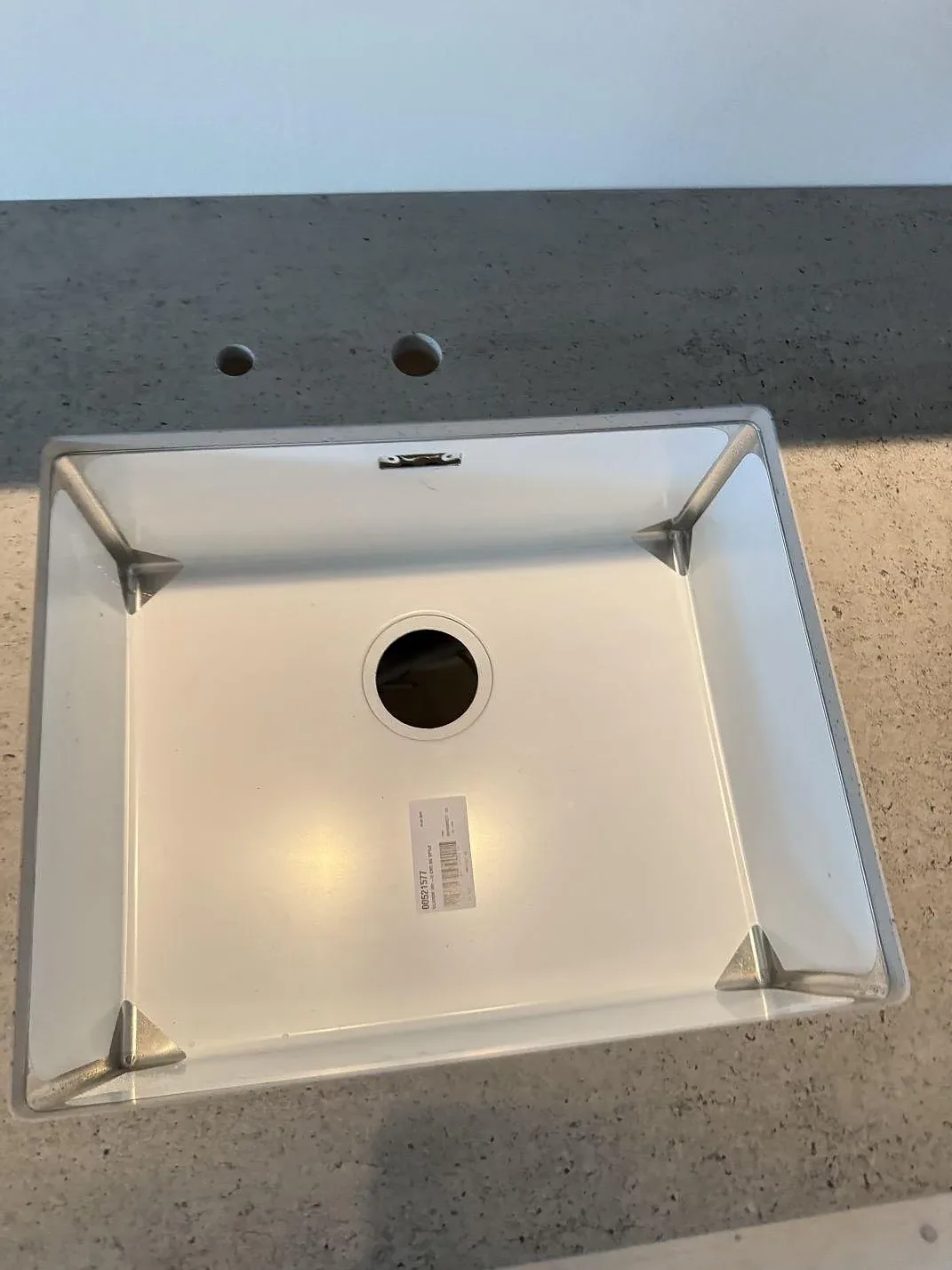 Närbild ovanifrån på diskho med borrade hål i köksbänkskiva av matt Dekton Keon, gråbeige keramik, i Hørsholm.