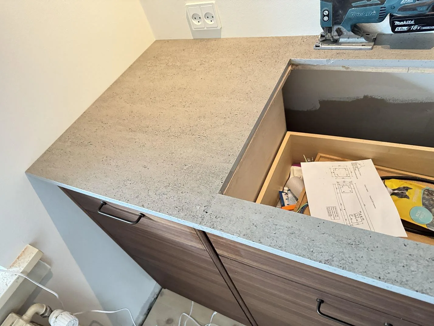 Köksbänkskiva i matt Dekton Keon runt ett öppet urtag, med ritning och trästomme synliga under montering i Hørsholm.