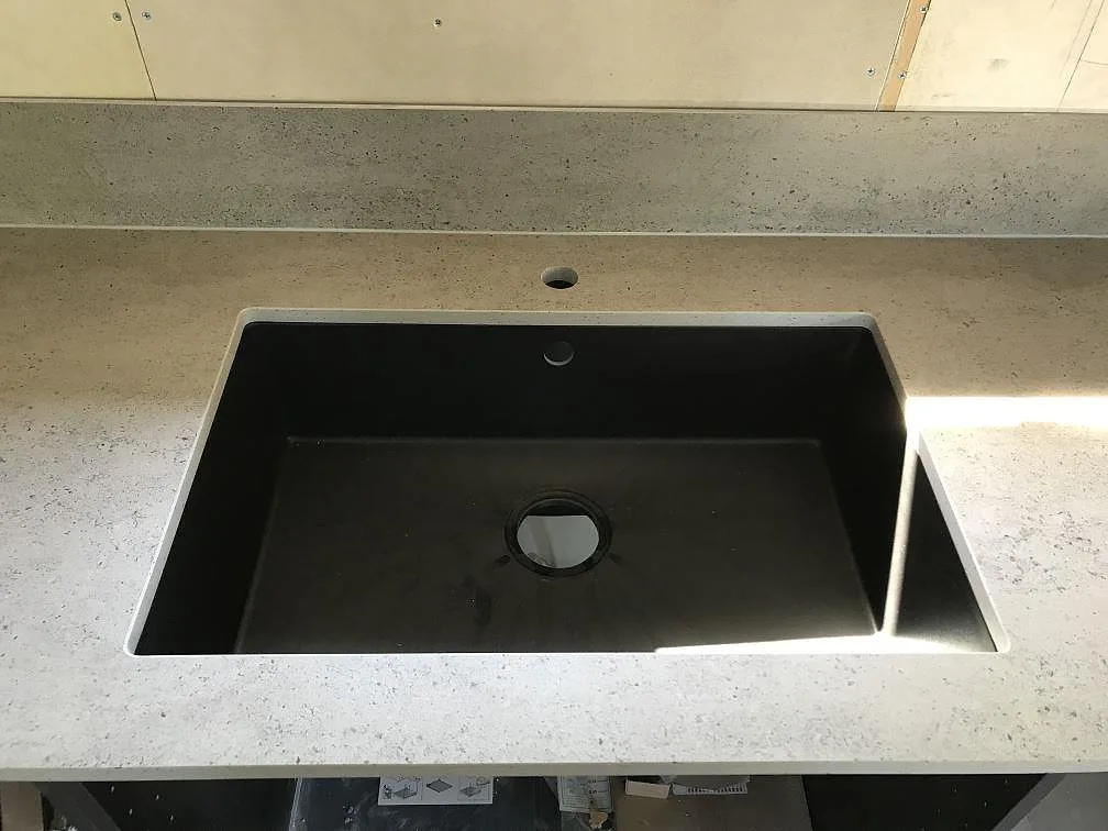 Närbild på underlimmad kompositdiskho med integrerad avrinningsyta i en köksbänkskiva av matt Dekton Keon i Höviksnäs.