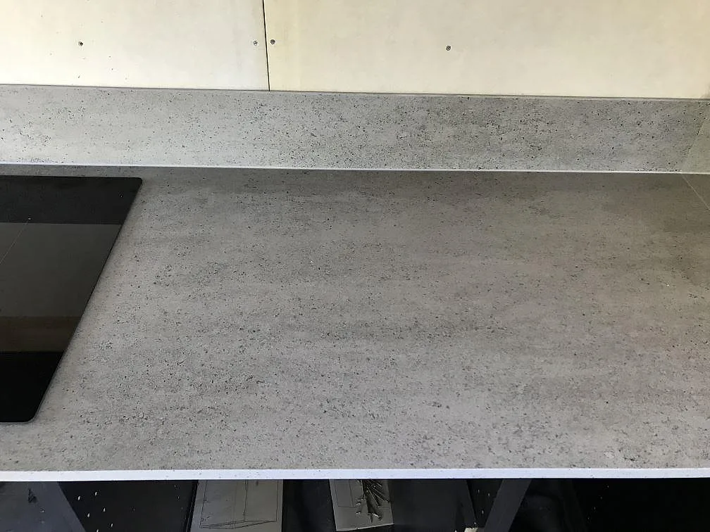 Bänkskiva i ljusgrå Dekton Keon med stänkskydd intill induktionshällen i ett kök under montering i Höviksnäs.