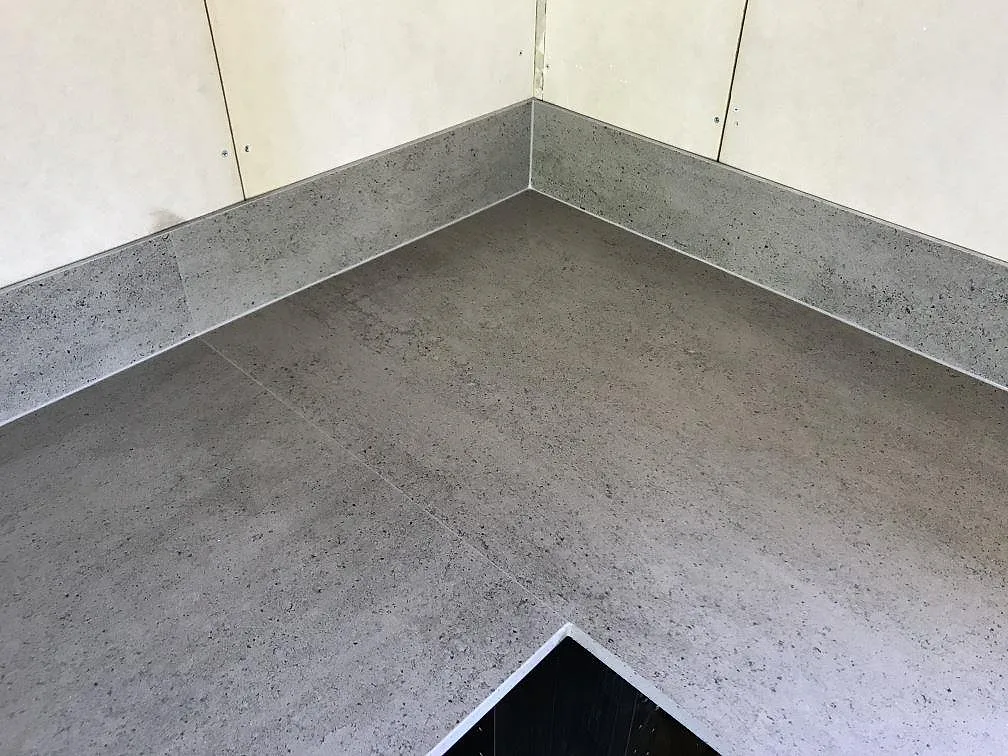 Köksbänkskiva i Dekton Keon med diskhoursnitt och heltäckande stänkvägg i matt cementlook i ett kök i Höviksnäs.