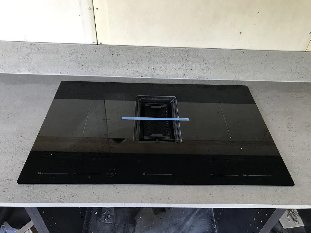 Infälld induktionshäll ovanifrån i en köksö av Dekton Keon i matt ljusgrå cementlook i ett kök i Höviksnäs.