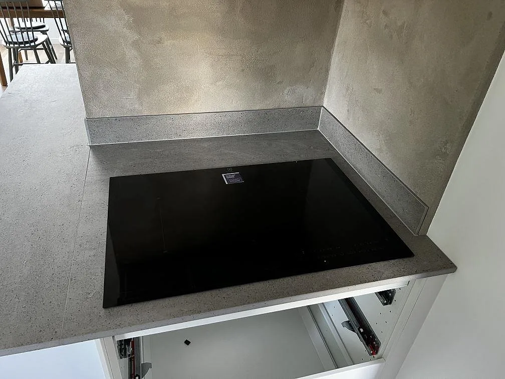 Detalj av matt Dekton Keon köksbänkskiva med svart induktionshäll och låg stänkkant i Kalmar.