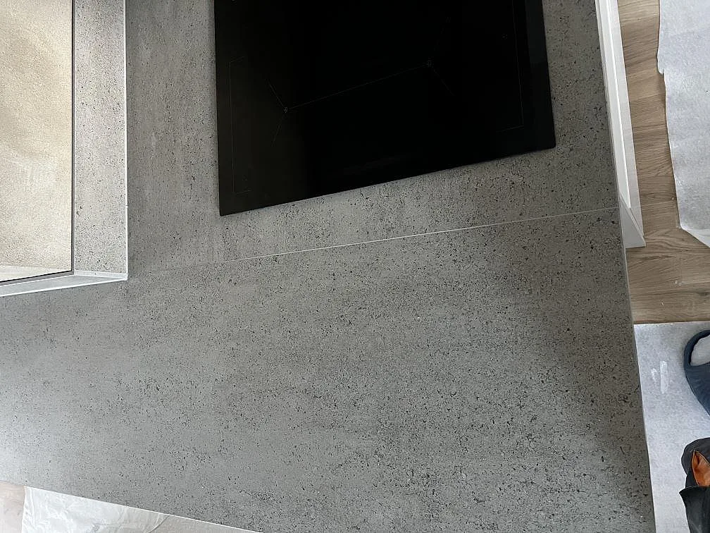 Närbild på matt Dekton Keon keramik vid svart induktionshäll och grå stänkkant i kök i Kalmar.