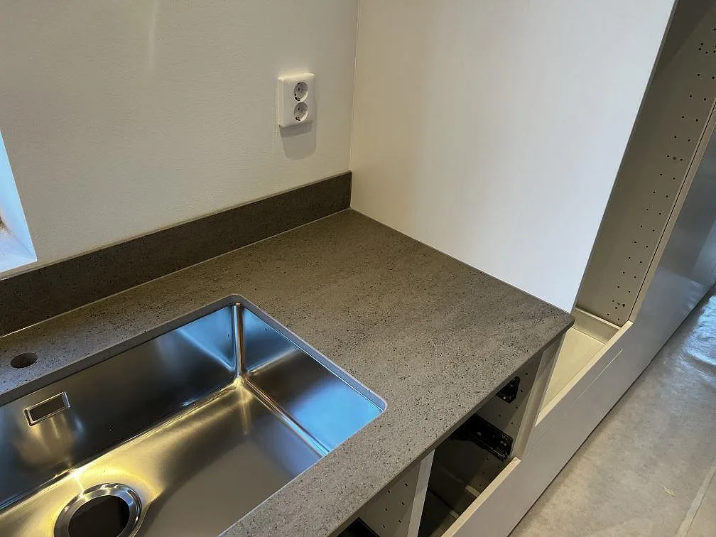 Närbild på matt Dekton Keon keramik runt en underlimmad rostfri diskho och stänkskydd i ett kök i Kalmar.