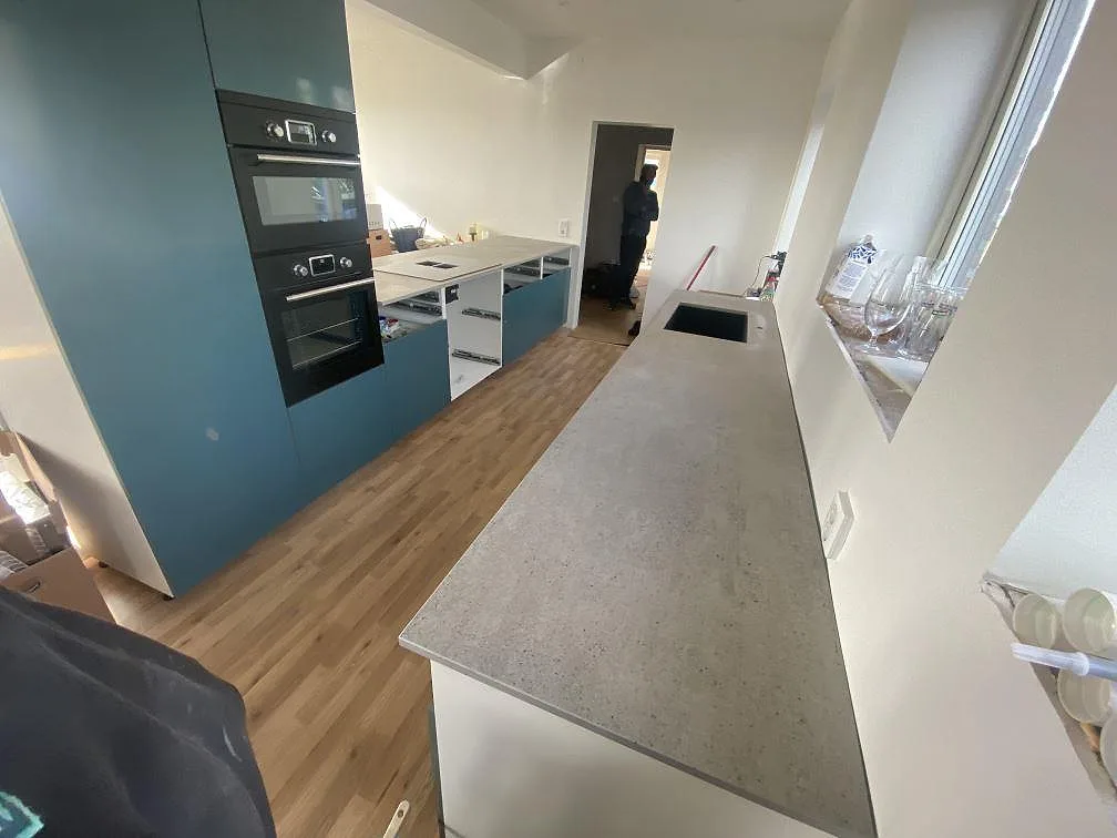 Grå betonglik köksbänkskiva i matt Dekton Keon med halvö i ett kök i Klagstorp, fotograferad under montering.