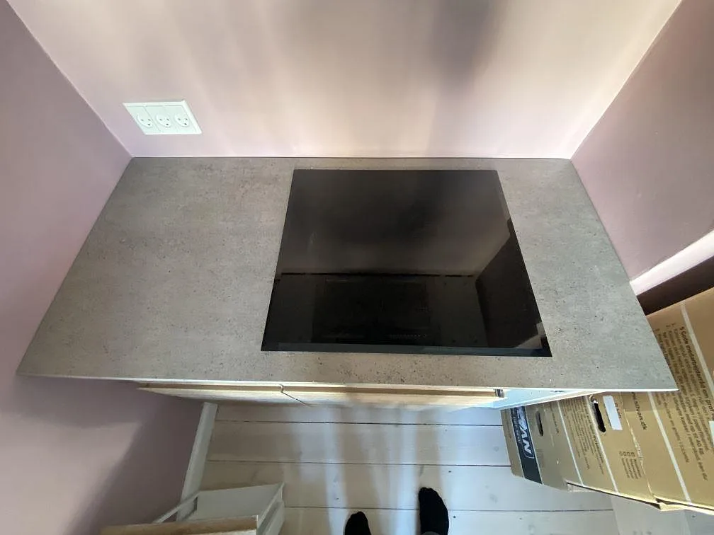 Köksbänkskiva i grå Dekton Keon med infälld svart induktionshäll i ett matt keramikkök i København Ø.