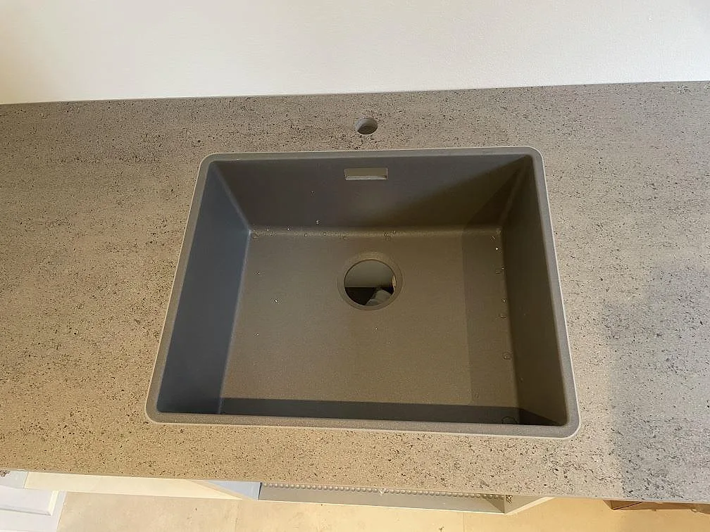 Underlimmad grå kompositdiskho infälld i en köksbänkskiva i Dekton Keon, matt finish, i Kr. Hyllinge.