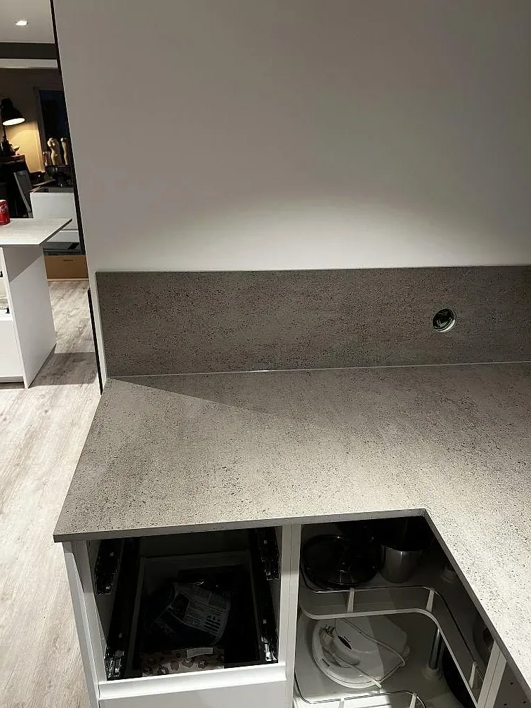 Bänkskiva i matt grå Dekton Keon i Kungsbacka med uppvikt väggbeklädnad och infälld bänkkontakt, fotograferat under montering.