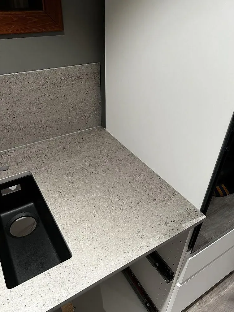 Hörn av köksbänkskiva i matt grå Dekton Keon i Kungsbacka med uppvikt stänkkant och svart underlimmad diskho.