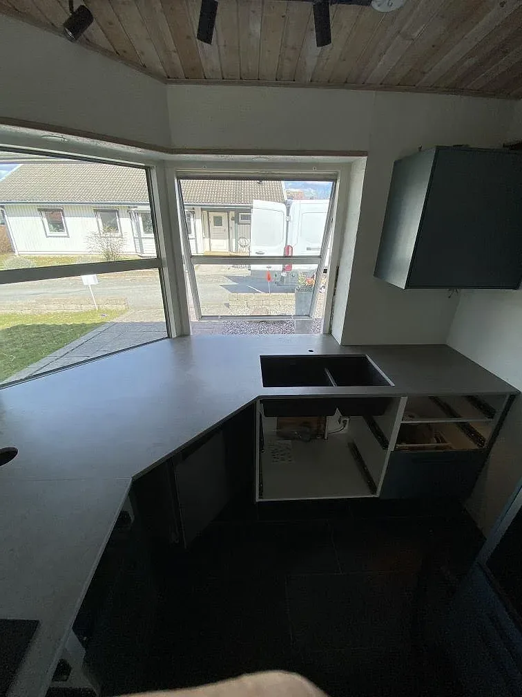 Grå köksbänkskiva i Dekton Keon med infälld induktionshäll, monterad i L-form med öppna stommar under monteringen i ett kök i Malmö.