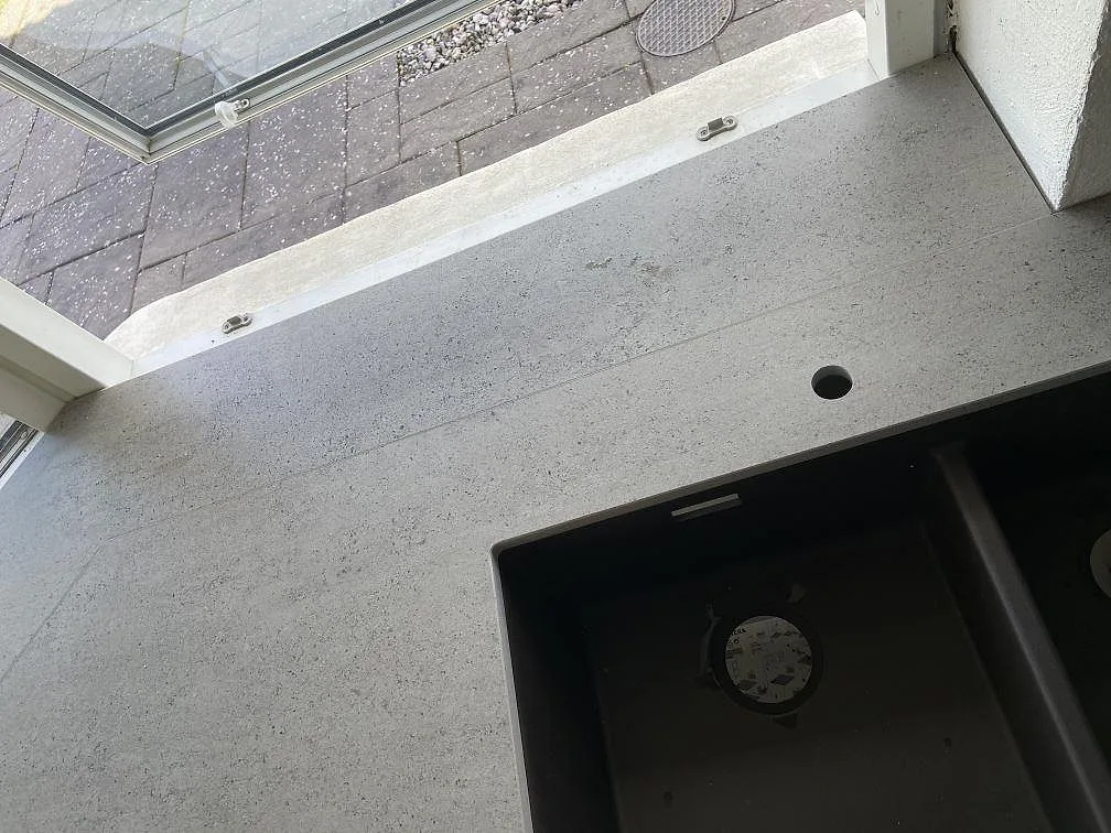 Köksbänkskiva i grå Dekton Keon med betonglook, matt yta, med underlimmad diskho i komposit och separat borrat blandarhål i ett kök i Malmö.