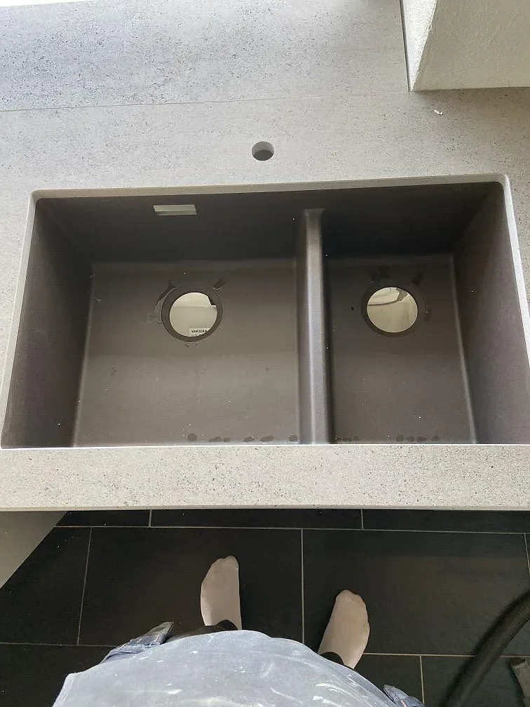 Underlimmad diskho i grå komposit i en matt köksbänkskiva i Dekton Keon med betonglook i ett kök i Malmö.
