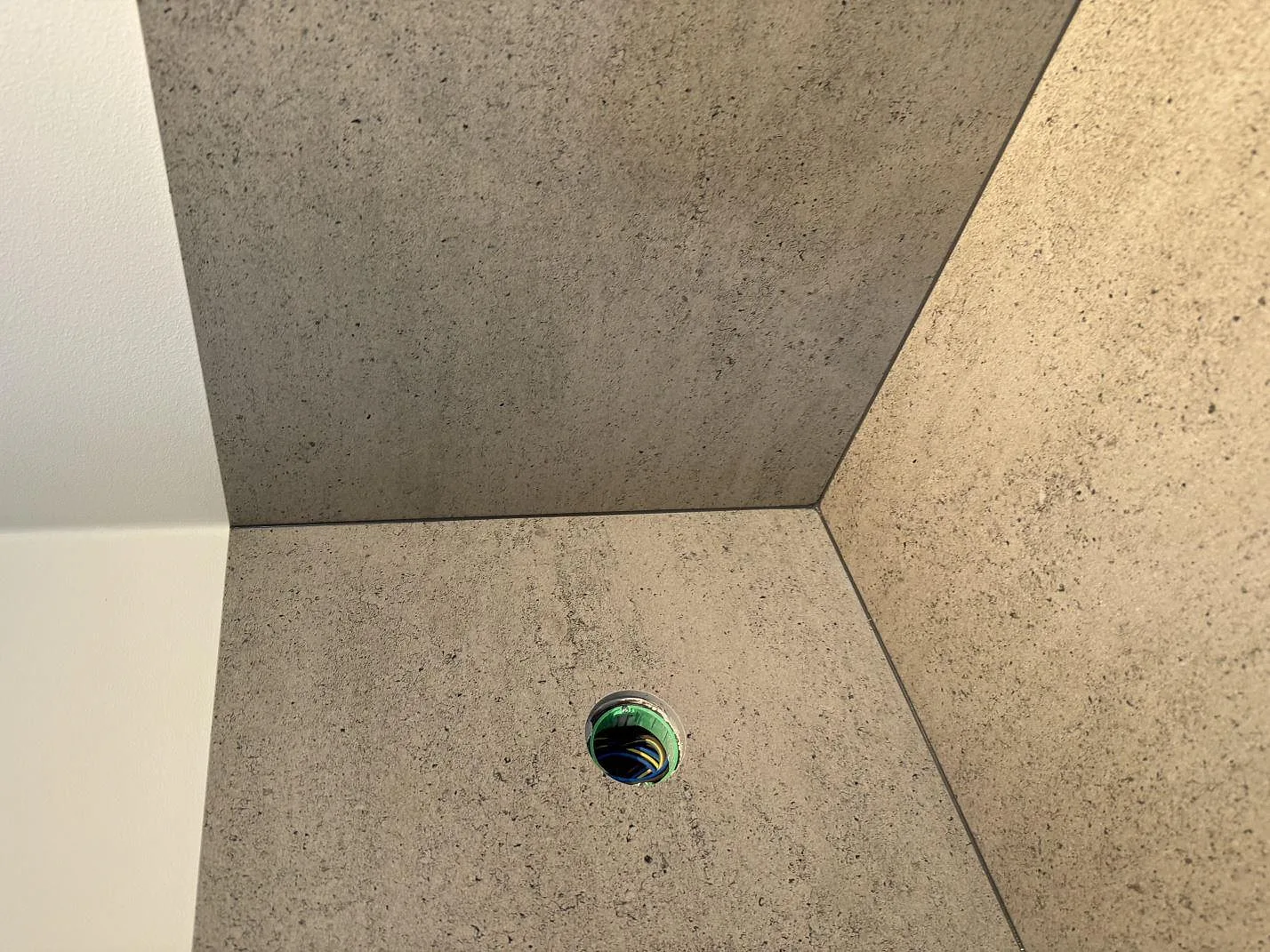 Närbild på hörn, elhål och stänkskydd i matt Dekton Keon vid köksbänkskiva i Malmö.