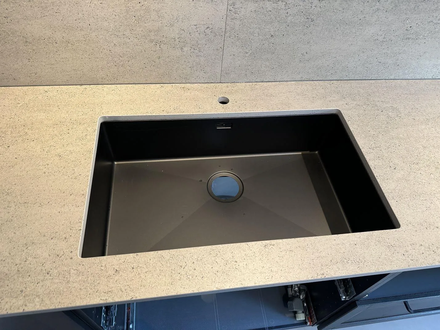 Närbild på svart diskho i en köksbänkskiva av matt Dekton Keon med stänkskydd i Malmö.
