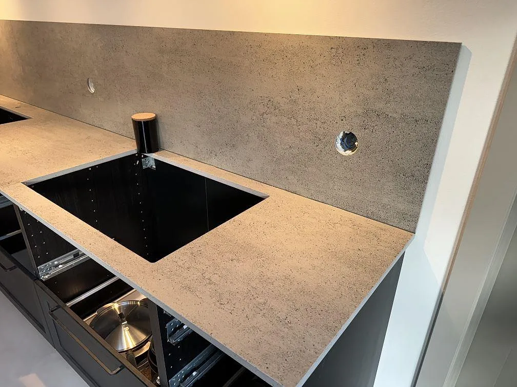 Bänkskiva och stänkskydd i matt Dekton Keon vid öppen köksstomme under montering i Malmö.