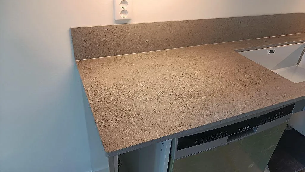 Diskbänksdel i matt Dekton Keon med vit underlimmad diskho och uppvikt stänkkant i ett kök i Östra Karup.