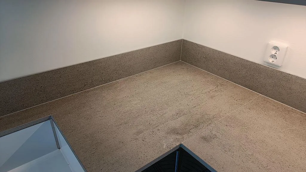 Hörn i U-format kök med matt Dekton Keon bänkskiva och matchande stänkskydd under överskåp i Östra Karup.