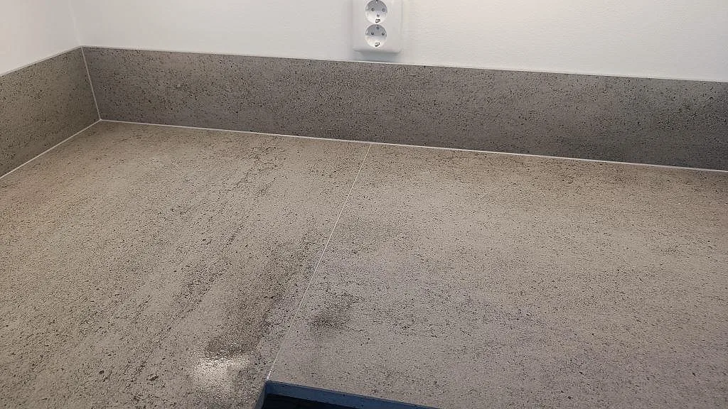 Materialdetalj av matt Dekton Keon bänkskiva med betonglik struktur och stänkskydd i Östra Karup.