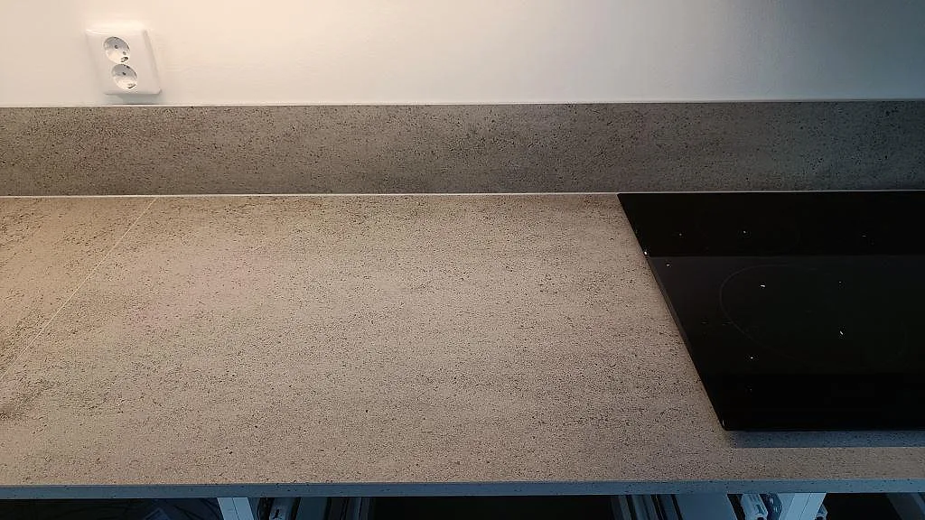 Rak bänkrad i matt Dekton Keon med svart induktionshäll och lågt stänkskydd i ett kök i Östra Karup.