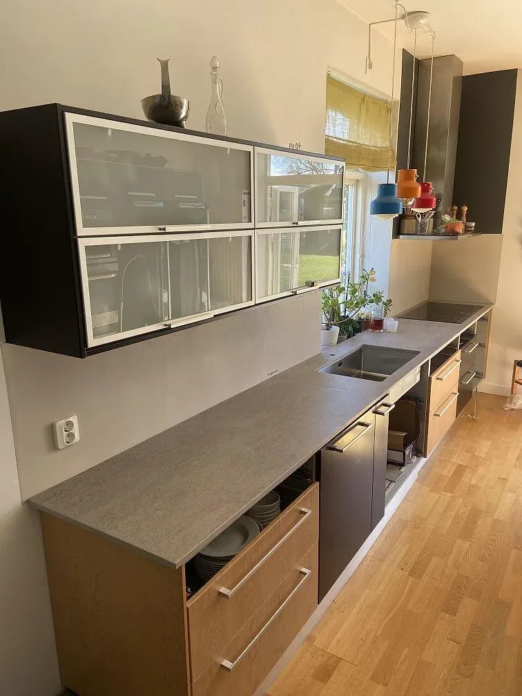 Köksbänkskiva i grå Dekton Keon med infälld svart induktionshäll i ett kök i Rinkaby, fotograferat under montering.