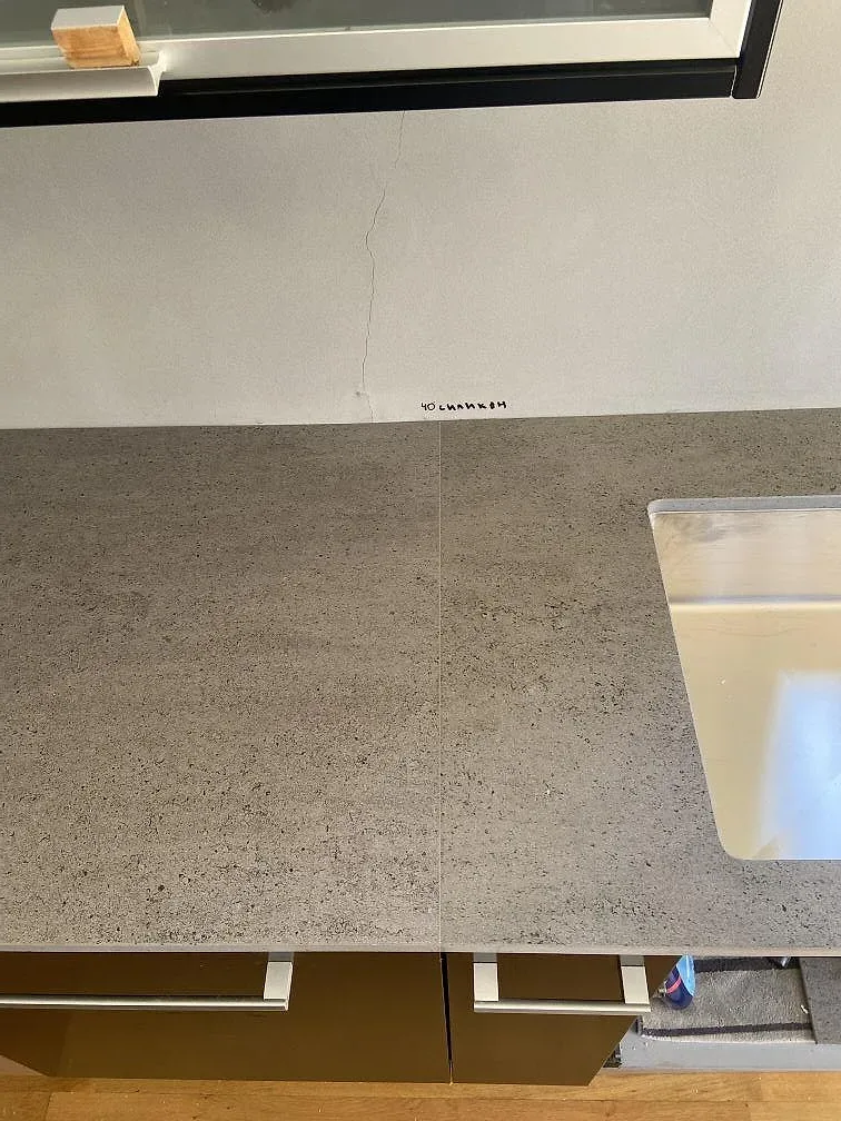 Underlimmad rostfri diskho i grå Dekton Keon köksbänkskiva vid ett fönster i ett kök i Rinkaby.