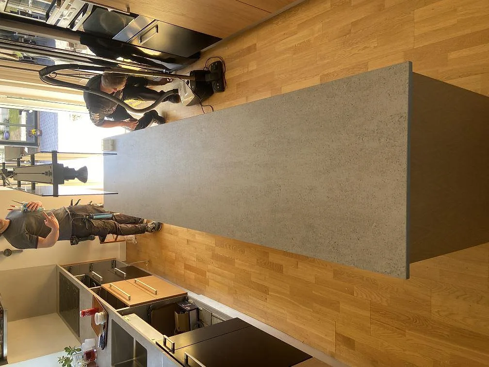Vägghög stenpanel i grå Dekton Keon med urtag i ett kök i Rinkaby, fotograferad under montering.