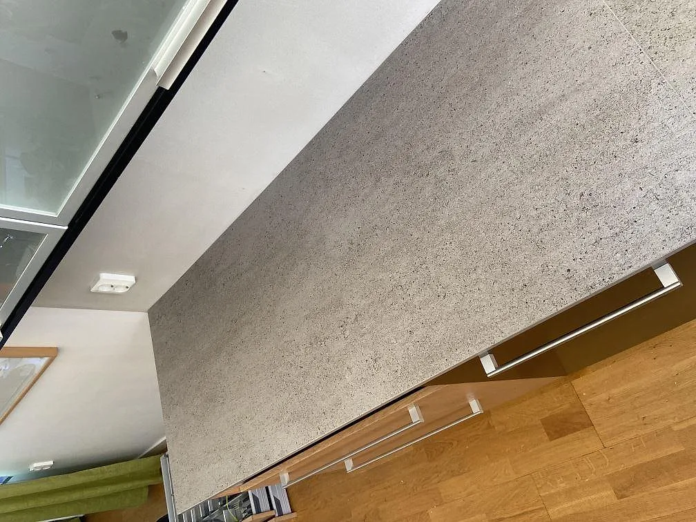 Närbild på kanten av en köksbänkskiva i grå Dekton Keon med matt yta i ett kök i Rinkaby.