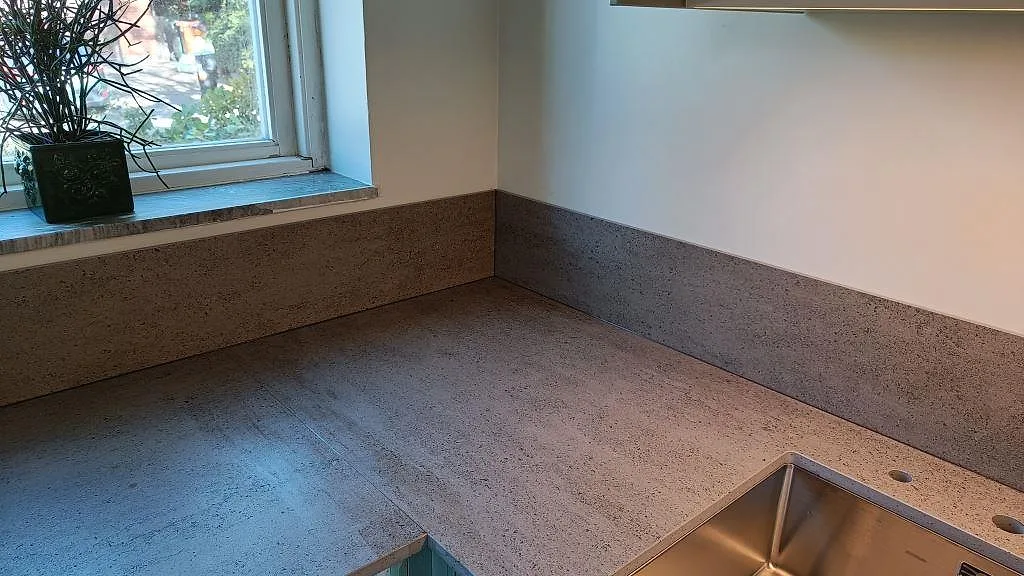 Matt Dekton Keon som köksbänkskiva i keramik och stänkskydd vid fönsterhörnet, med diskho i kanten, i Sävedalen.