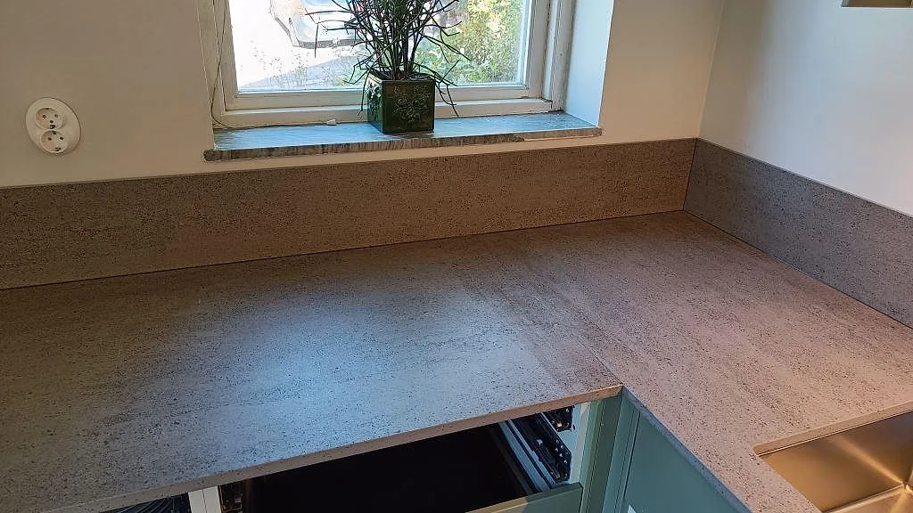 L-formad köksbänkskiva i matt Dekton Keon, keramik, med stänkskydd och fönsternisch i Sävedalen.