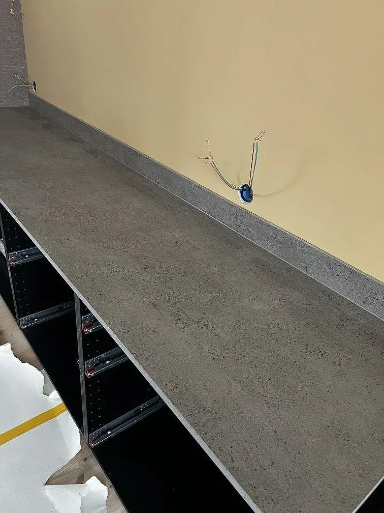 Grå betonglik Dekton Keon köksbänkskiva, matt, monterad ovanpå öppna stommar i ett kök under installation i Stora Höga.