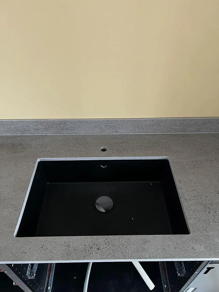 Underlimmad svart komposithoar i grå Dekton Keon köksbänkskiva, matt, med separat tapphål, fotograferad under montering i Stora Höga.