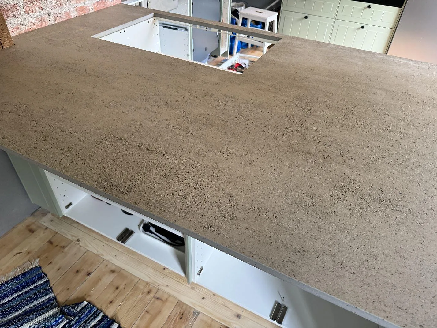 Lång arbetsyta i matt Dekton Keon på vita köksstommar med synlig grå keramikyta i Trollhättan.