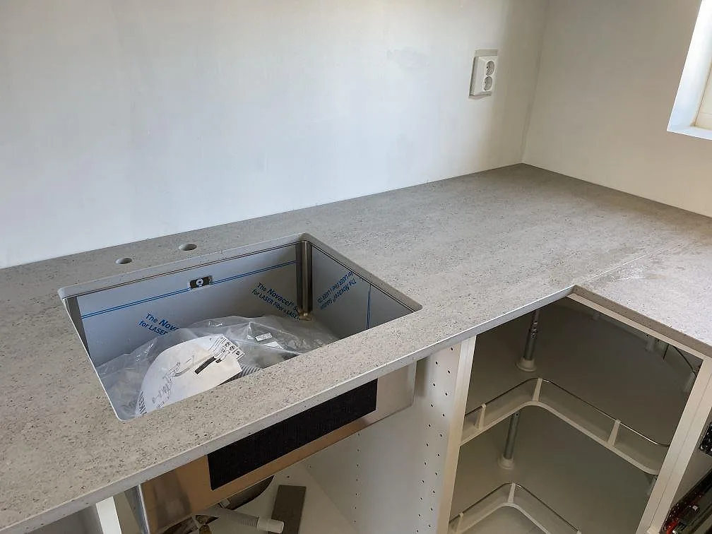 Köksbänkskiva i grå Dekton Keon keramik, matt, med dubbel underlimmad diskho under montering i Tygelsjö.