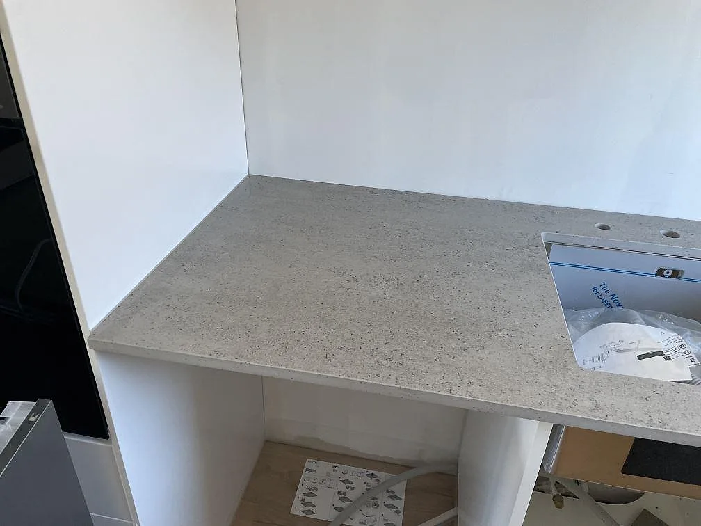 Rak köksbänkskiva i Dekton Keon keramik, matt, med diskho och öppen köksstomme under montering i Tygelsjö.