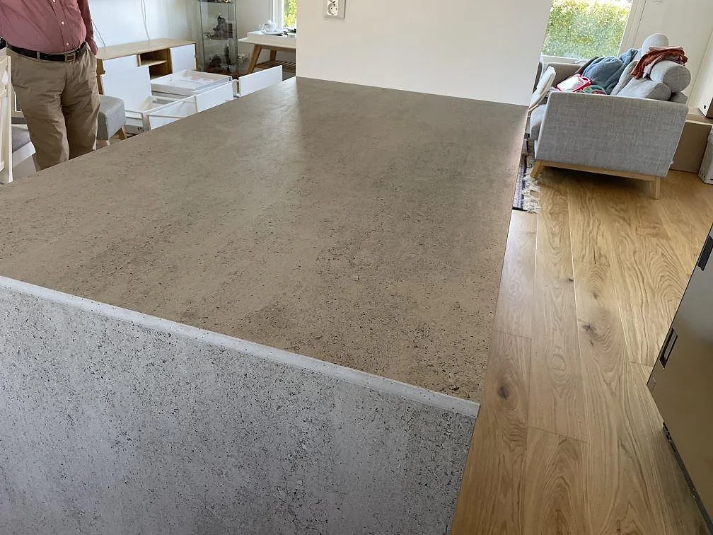 Stor köksö i grå Dekton Keon keramik, matt, med vattenfallsida och vit köksinredning i Tygelsjö.