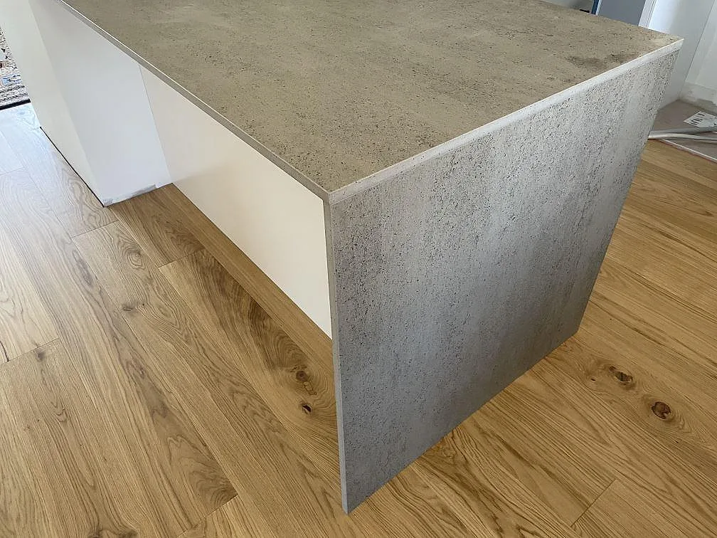 Köksö i grå Dekton Keon keramik, matt, med vattenfallsida mot ljust trägolv i Tygelsjö.
