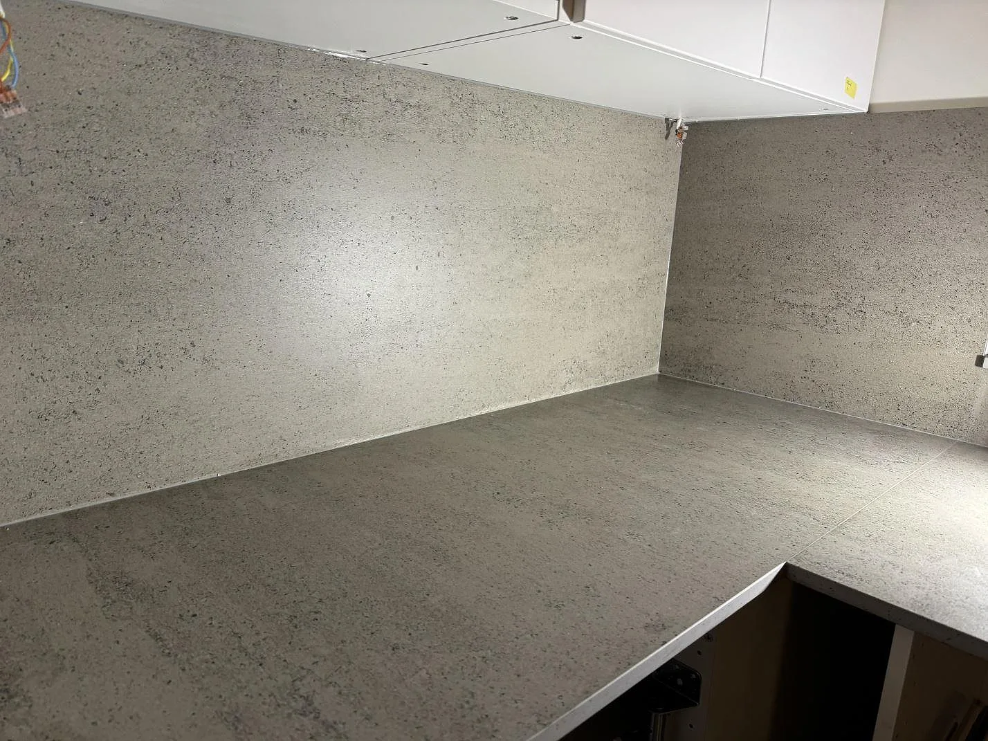 Hörnmonterad köksbänkskiva i matt Dekton Keon med matchande väggfält i Tygelsjö.