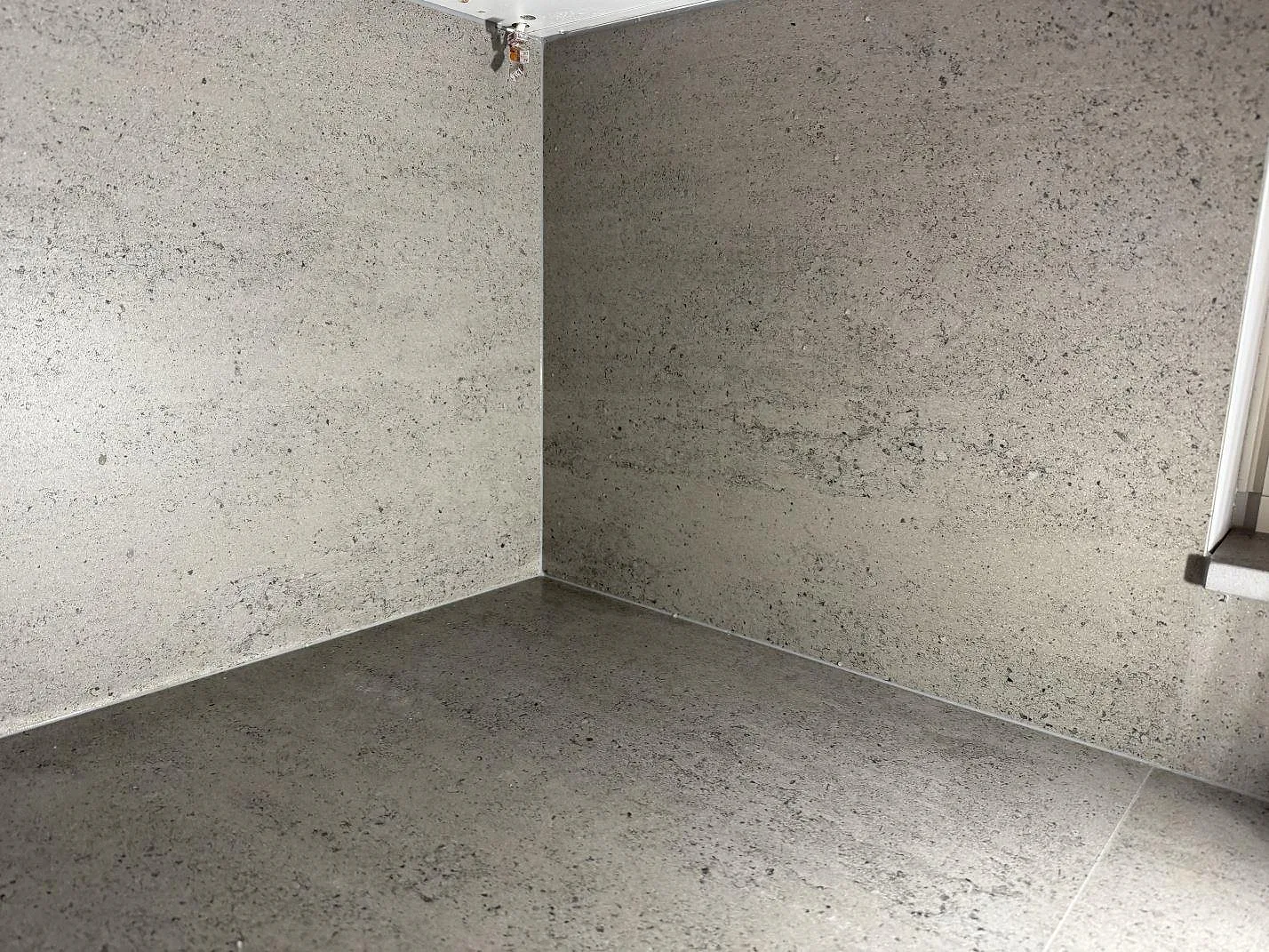 Detalj av matt Dekton Keon som bänkskiva och väggfält i ett kök under montering i Tygelsjö.