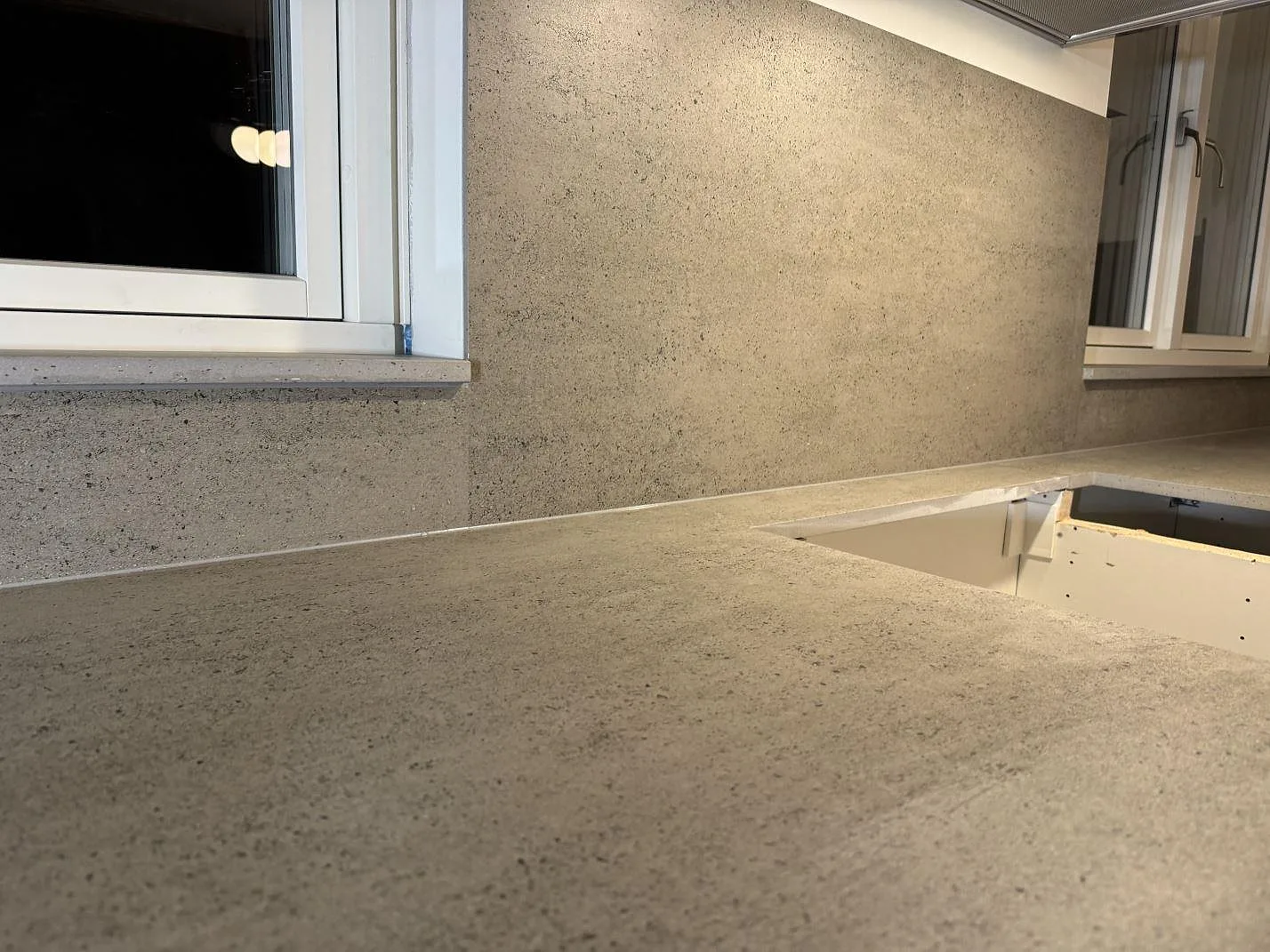 Köksbänkskiva i matt Dekton Keon med fönsterbänk och väggfält längs ett kök i Tygelsjö.