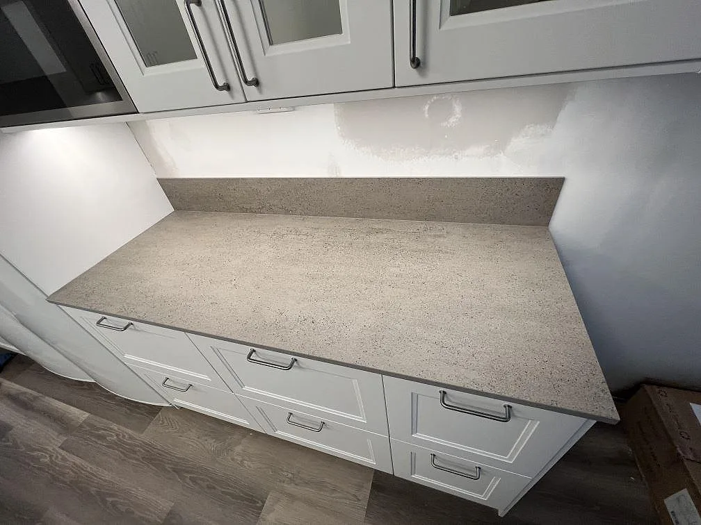 Rak köksbänkskiva i matt Dekton Keon, keramik, med låg stänkkant och vita köksluckor i Västerås.