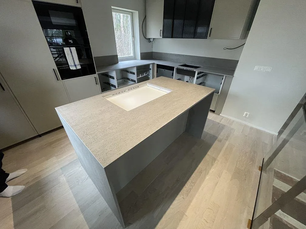 Köksbänkskiva i ljusgrå Dekton Keon, matt keramik, med köksö, diskplats och häll i ett kök i Västerås.