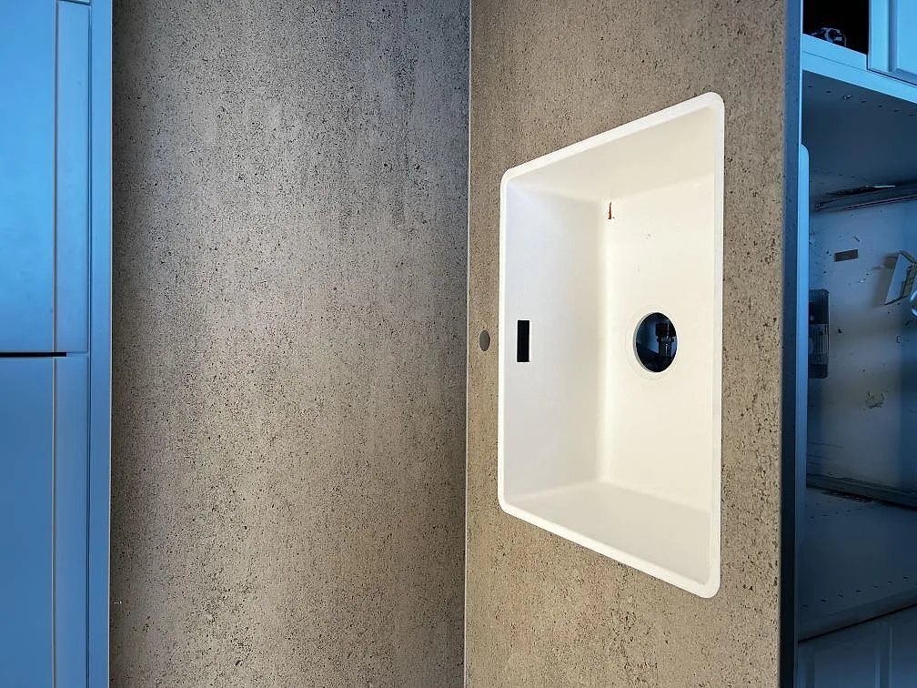 Köksbänkskiva i Dekton Keon, matt soft grey betonglook, med vit underlimmad diskho i ett kök i Västra Frölunda.